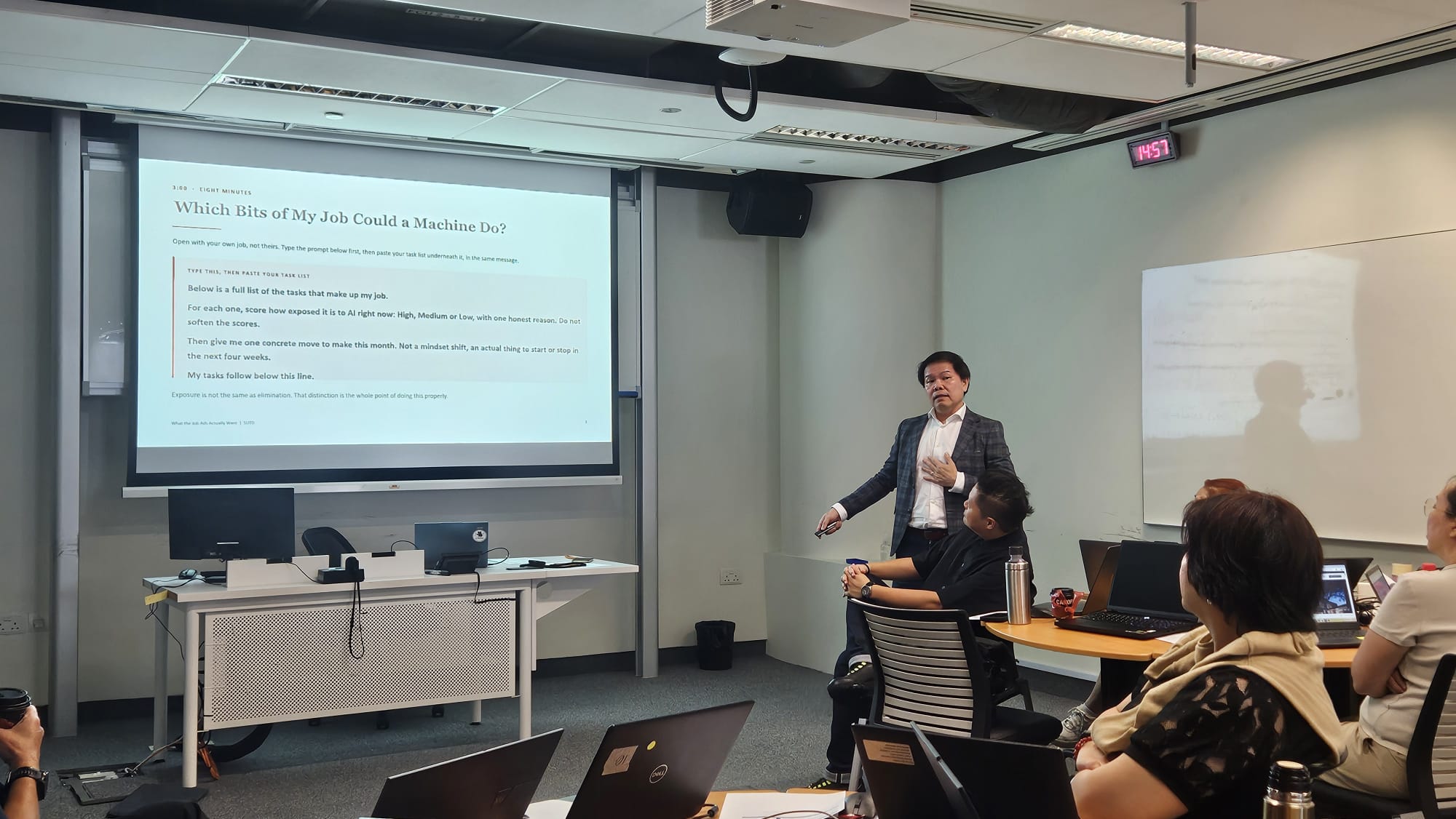 Damien Goh leading a hands-on AI session with participants at laptops at SUTD